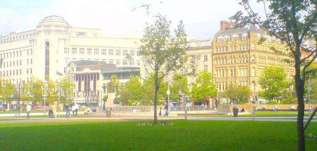 Grass town square and trees watered using pop-up urban irrigation system providing a regular water supply