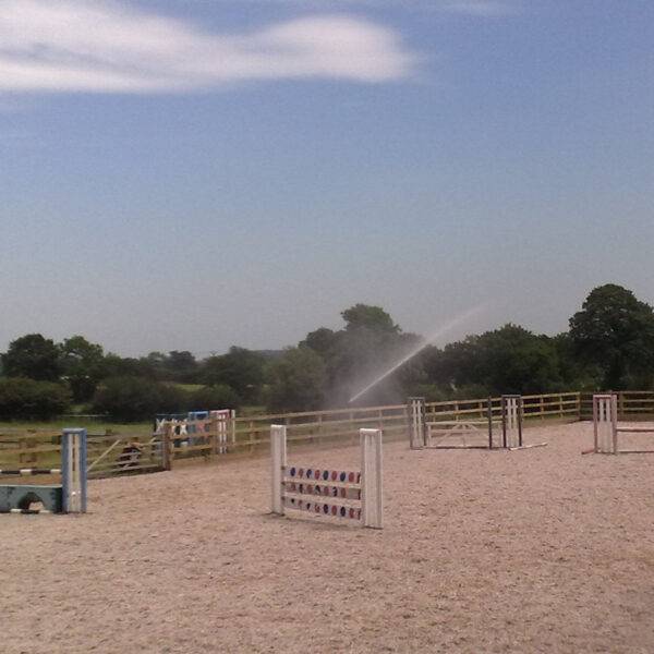 Large sprinkler watering horse arena to reduce dust problems for both horse and rider