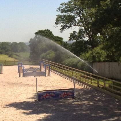 Large sprinkler watering horse arena to reduce dust problems for both horse and rider