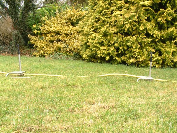 Lawn and borders with trees watered using moveable metal sled sprinkler risers with Naan 501 sprinklers connected by Tricoflex hose