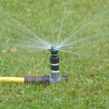 Lawn watered by spiked metal lawn sprinkler with professional quality nozzle connected to Tricoflex hose using 'snap-on’ hose connector fitting