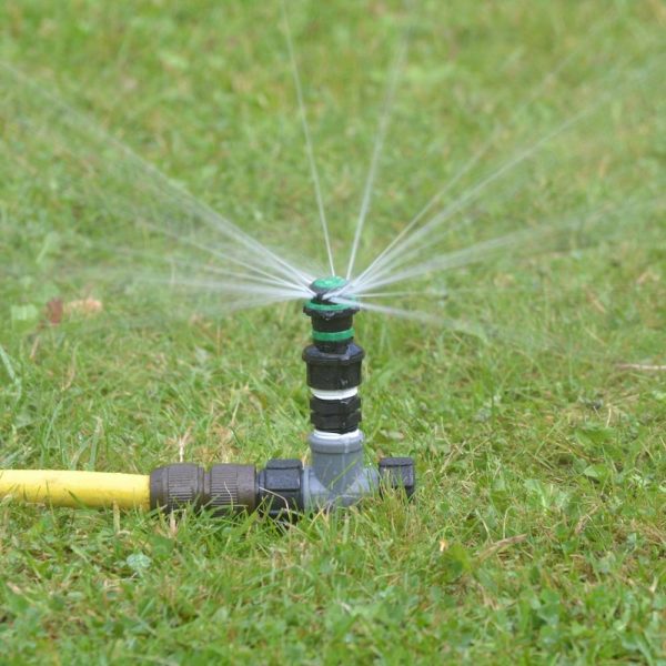 Lawn watered by spiked metal lawn sprinkler with professional quality nozzle connected to Tricoflex hose using 'snap-on’ hose connector fitting
