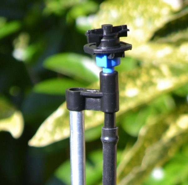 Close up image of sprinkler on tall spike riser for watering garden borders